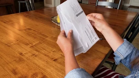 Official Mail in Ballot, woman opens envelope to vote from home during Stock Footage