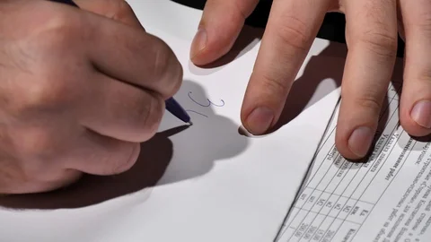 An official writes the amount of a bribe on a white sheet. Stock Footage 129786669