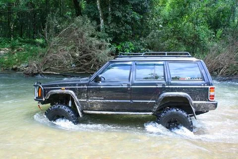 Offroad car crossing river Stock Photos