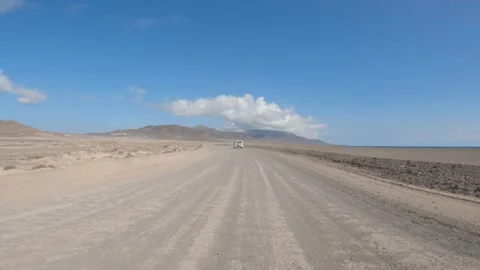 Offroad car driving on a dirt track follow shot with small clouds of dust Stock Footage 175699103