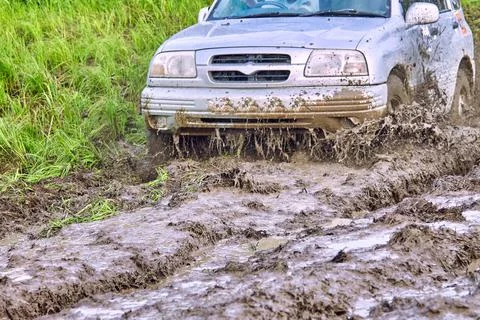Offroader is driving across the field, splashes of slush flying in all direction Stock Photos