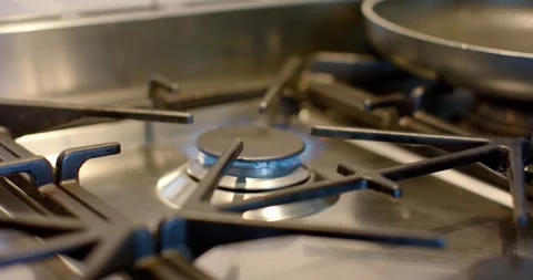 Offscreen turning knob in kitchen igniting stainless steel burner lighting blue 库存影片 340257013