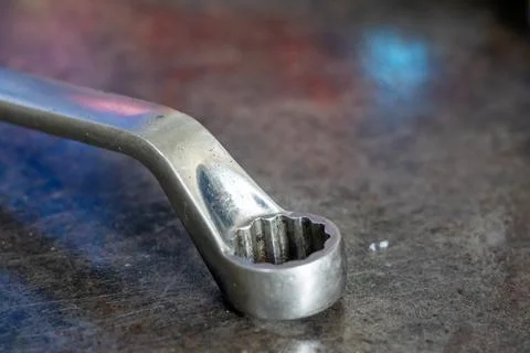 Offset box end wrench head lies on scratched metal workbench in mechanical .. Stock Photos