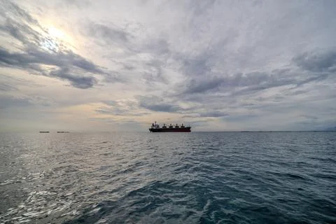 Offshore Cargo Vessel Floating on Calm Ocean Waters. Dramatic sky and sea i.. Stock Photos