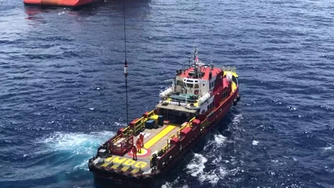 Offshore crew boat performing cargo operations with oil rig crane Stock Footage 143125564