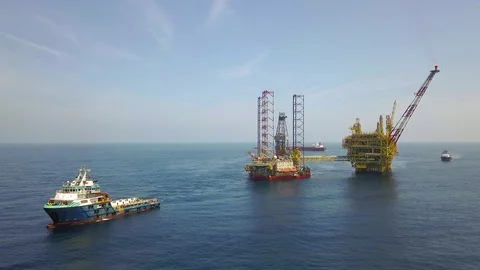 Offshore jack-up drilling rig preparing for a move by towing boat Stock Footage 100054951
