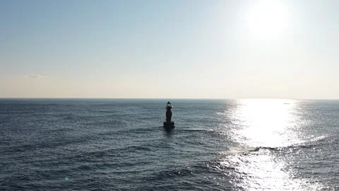Offshore Lighthouse Silhouette in Sunlit Ocean, Aerial View Stock Footage 344778139