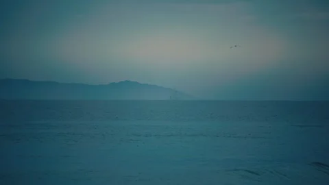 An offshore oil platform stands on the distant ocean horizon beneath clouds Stock Footage 347978792