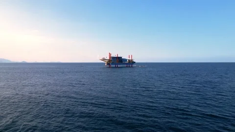 An offshore oil rig in the middle of the ocean, towering over the surrounding Stock Footage 239927875
