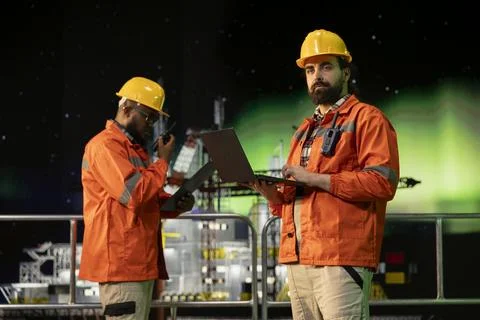 Offshore platform worker uses laptop software during aurora borealis night Stock Photos