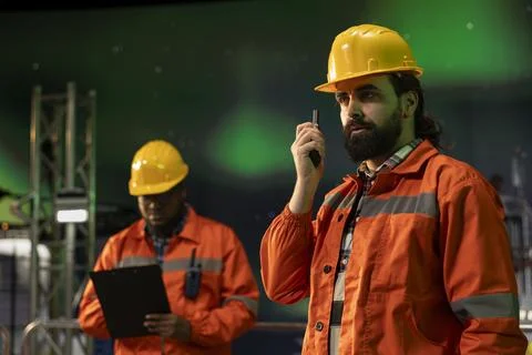 Offshore platform worker using walkie talkie, aurora borealis background Stock Photos