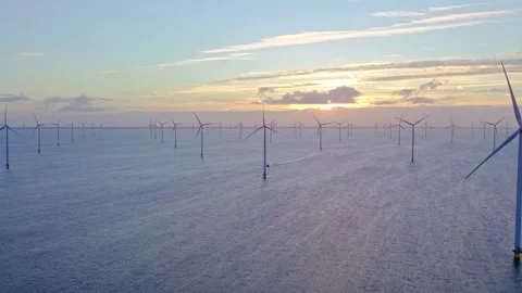 Offshore wind farm turbines generating sustainable energy at sunset over calm Stock Footage 343696173