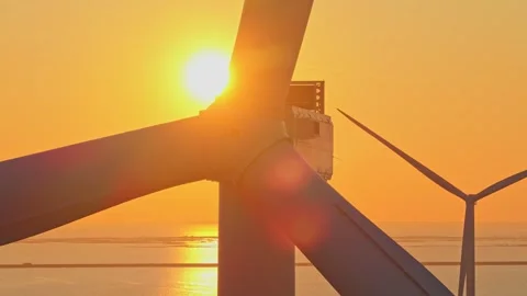 Offshore wind turbine blades rotating at sunset Stockbeeldmateriaal 333648955