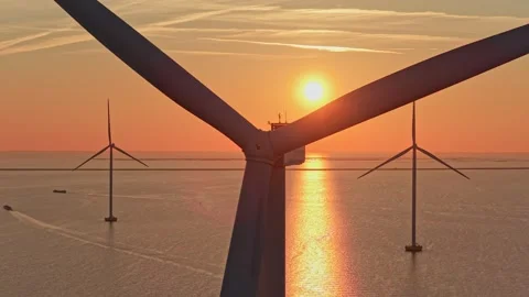Offshore wind turbine generating renewable energy at sunset Stock Footage 333648944
