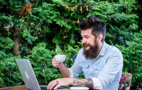 Offsite work. Hipster drinking tea and using computer work station outdoor Stock Photos