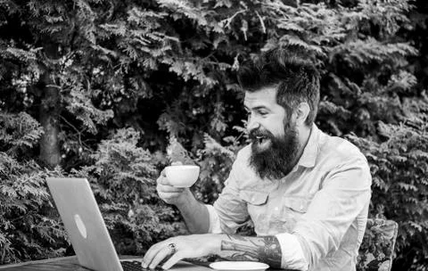 Offsite work. Hipster drinking tea and using computer work station outdoor Stock Photos