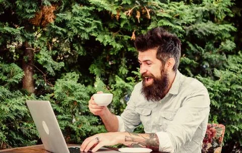 Offsite work. Hipster drinking tea and using computer work station outdoor Stock Photos