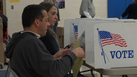 Ohio man seated at booth studies paper ballot. Stock Footage 106159391