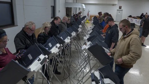 Ohio voters stand at two rows of elelctronic terminals. Stock-Footage 106036185