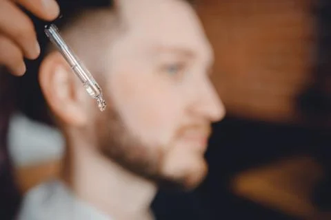Oil for beard in dropper, process of moisturizing hair. Home care for mustache Stock Photos