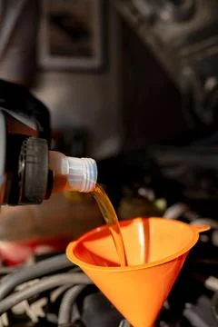 Oil change in progress with orange funnel. Stock Photos