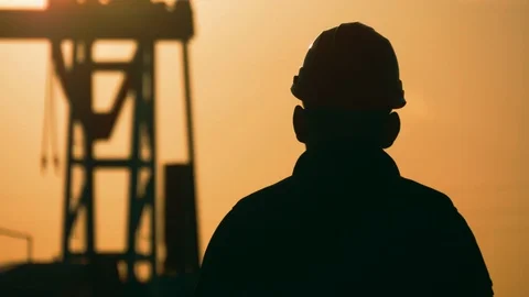 Oil drill, field pump jack silhouette with setting sun and worker. Oil field Stock Footage