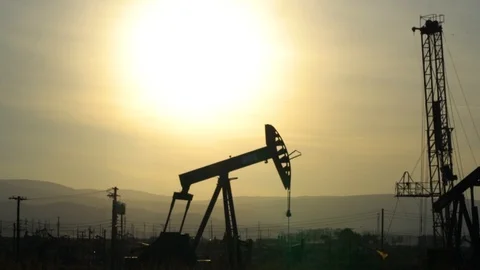 An oil drill in silhouette in the Kern River oil field in California Stock Footage