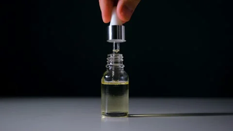 Oil drops falling from the pipette, on the black background.  Stock Footage 153672834