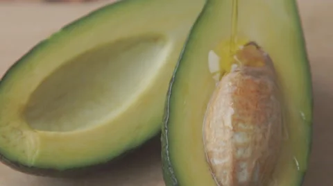 Oil drops over a half cut avocado on a table Stock Footage 68957190