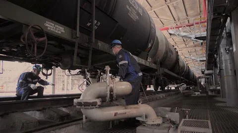 Oil engineer mounts drain valve hgerfd to railroad tanker Stock Footage 212389796