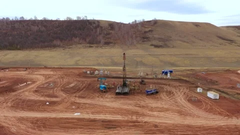 Oil field development. A drilling rig among the hills on a cloudy autumn day. Video stock 168122019