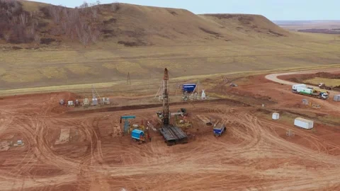 Oil field development. A drilling rig among the hills on a cloudy autumn day. Stock Footage 168550846