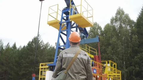 Oil field technical worker standing with his back to camera and in front of Vídeos de archivo 127662407