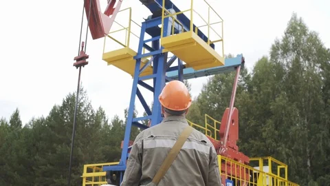 Oil field technical worker standing in front of crude oil pump unit. Engineer in Vídeo Stock 127662538