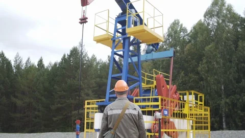 Oil field technical worker standing in front of crude oil pump unit. Engineer Stock Footage 127662733