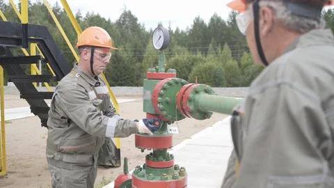 Oil field technical workers opening or closing valve of wellhead. Injection tree Video stock 127663535