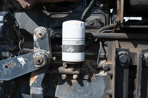 Oil filter mounted upside down on the side of a typical working farm tractor Stock Photos