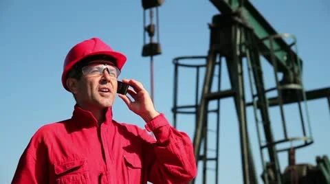 Oil Industry Worker Using Cell Phone Next to Pump Jack Stock Footage 12467150