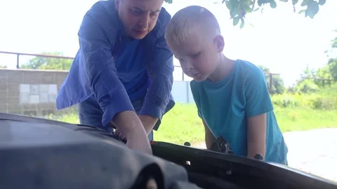 Oil level check. A man shows his son how to check the oil level in a car engine. Stock Footage 243077583