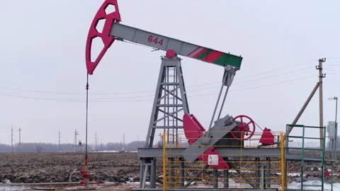 An oil pump in a field pumps raw product for sale and processing Stock Footage 238074802