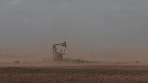 An oil pump jack almost hidden by blowing dust, 4K. Stock Footage 243904180