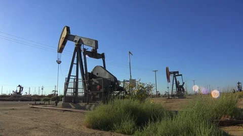 Oil pump jack operating on a clear day, extracting petroleum from the earth.. Stock Footage 337806268