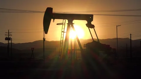 Oil pump jack operating at sunset in desert landscape with mountains on hor.. Stock Footage 337756331