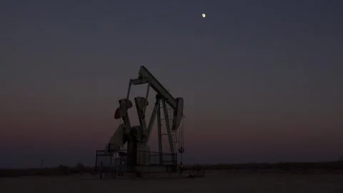 Oil pumpjack operates in desolate landscape under fading twilight sky with .. Stock Footage 337805818