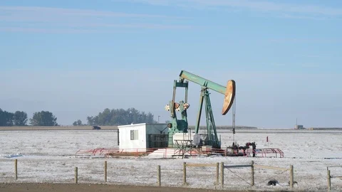 Oil pumpjack operating in a snowy field on a foggy morning Stock Footage 117961646