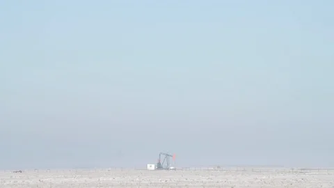 Oil pumpjack operating in a snowy field on a foggy morning Stock Footage 117964918