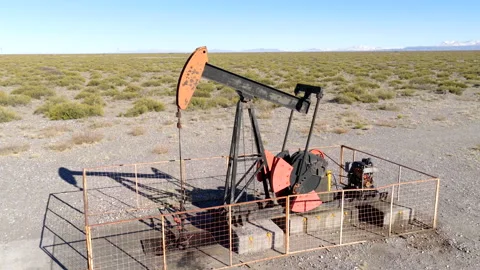 Oil pumpjack operating in Vaca Muerta shale region, Argentina surrounded by dry Stock Footage 312592826