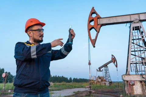 Oil refining. A man takes a sample of oil at an oil field Stock Photos