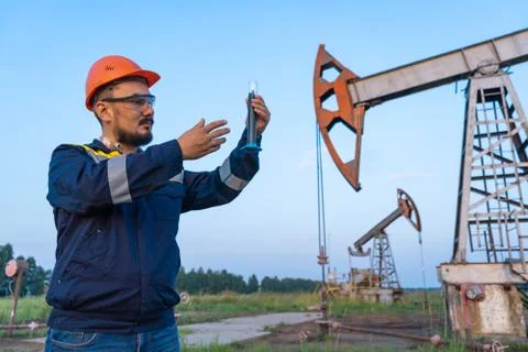 Oil refining. A man takes a sample of oil at an oil field Stock Photos
