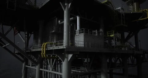 Oil rig structure illuminated at night above calm ocean waters Stock Footage 308261234